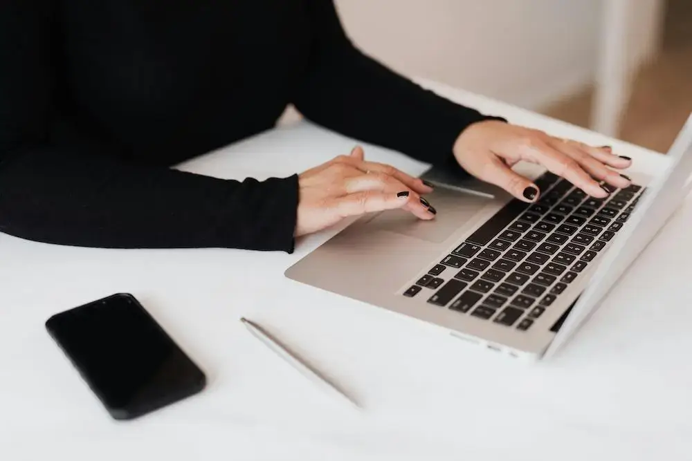 Woman working on the laptop with a phone on the desk